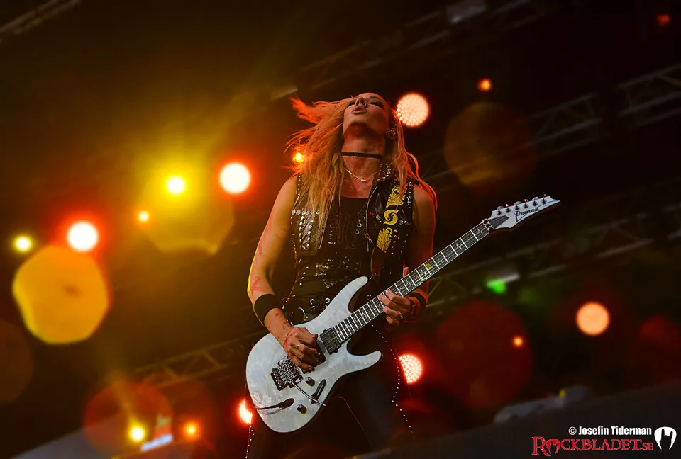 Gitarrist med vit gitarr i gult och rött scenljus