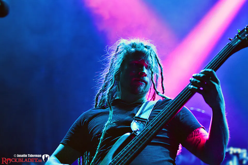Basist med dreadlocks i rosa och blått scenljus